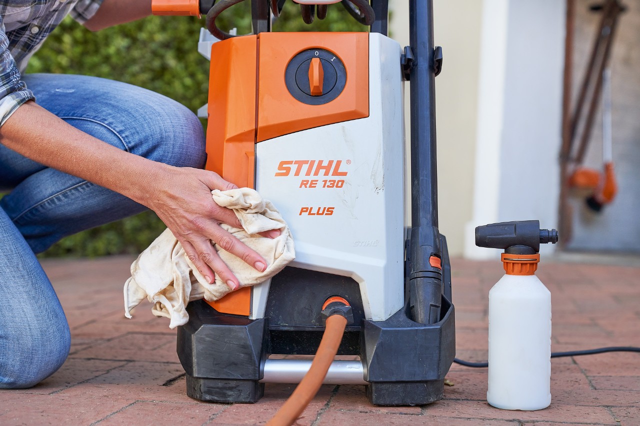A woman treating the STIHL RE 130 PLUS high-pressure cleaner with anti-freeze for high-pressure cleaner maintenance