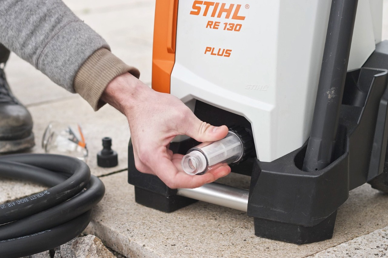 A person checking the connection of a STIHL RE 130 PLUS high-pressure cleaner